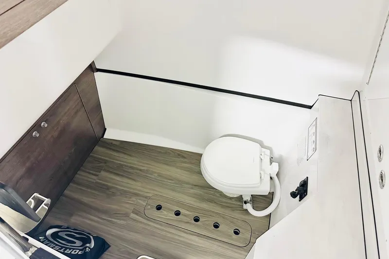 Slide: The Image of 2026 Sportsman Heritage 321 Center Console boat interior with modern toilet and wood flooring. - 9