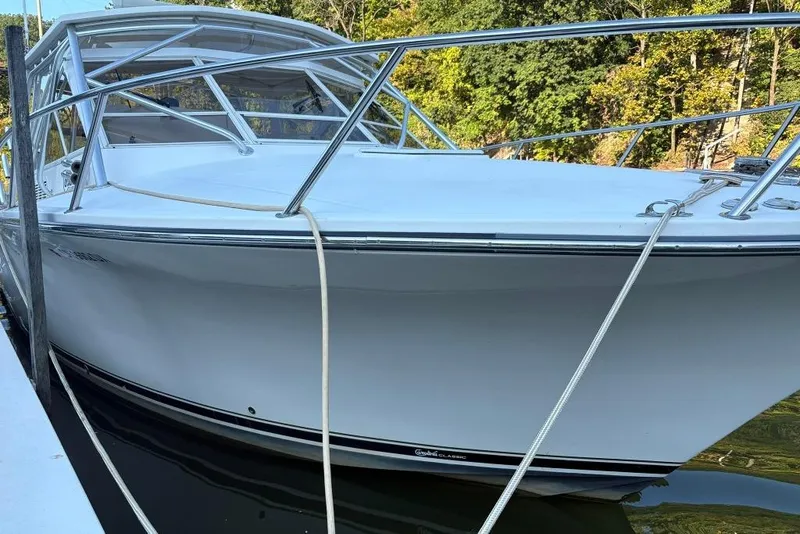 Slide: The Image of 2006 Carolina Classic 32 boat docked, featuring sleek white design and sturdy railings. - 2