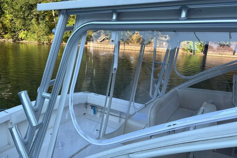 Slide: The Image of 2006 Carolina Classic 32 boat interior with seating and rod holders, near a scenic shoreline. - 3