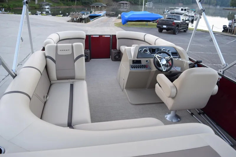 Slide: The Image of 2024 Crest Classic LX 200 L pontoon boat interior with plush seating and modern helm. - 6