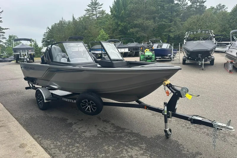 Slide: The Image of 2025 Crestliner 1750 Hawk boat on trailer, parked outdoors with other boats nearby. - 4