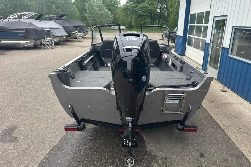 Slide: The Image of 2025 Crestliner 1750 Hawk boat with Mercury 115 engine, parked near a blue building. - 6