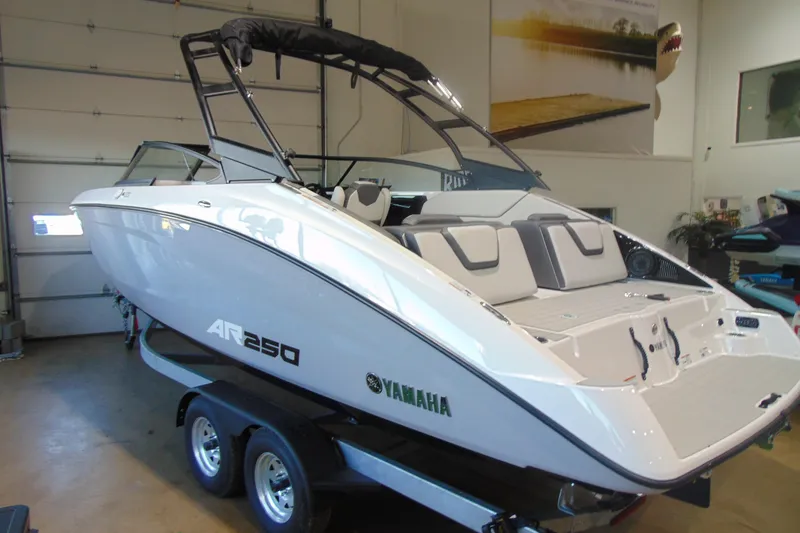 The Image of 2026 Yamaha Boats AR250 in showroom, sleek design, white exterior, on trailer. - 10
