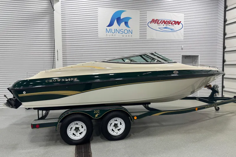 The Image of 1998 Crownline 202 BR boat on trailer in showroom, Munson Ski & Marine signs visible. - 1