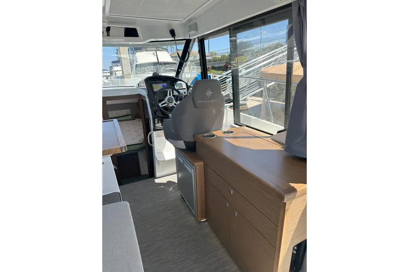 Slide: The Image of Interior of 2021 Jeanneau NC895 boat with helm, seating, and wooden cabinetry. - 11