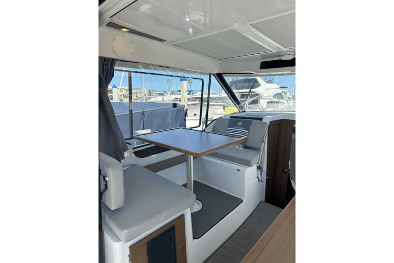Slide: The Image of Interior of 2021 Jeanneau NC895 boat with seating and table, docked at marina. - 2