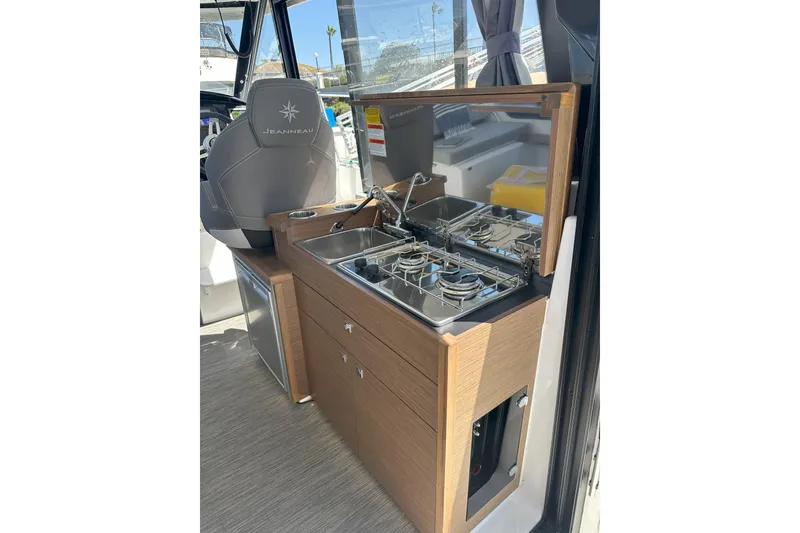 Slide: The Image of Compact kitchen area in a 2021 Jeanneau NC895 boat, featuring a stove and sink. - 24