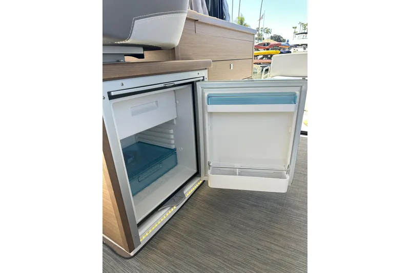 Slide: The Image of Open refrigerator inside 2021 Jeanneau NC895 boat, showcasing interior storage space. - 28