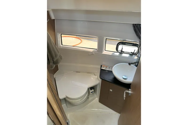 Slide: The Image of 2021 Jeanneau NC895 boat bathroom with compact toilet, sink, and windows. - 35