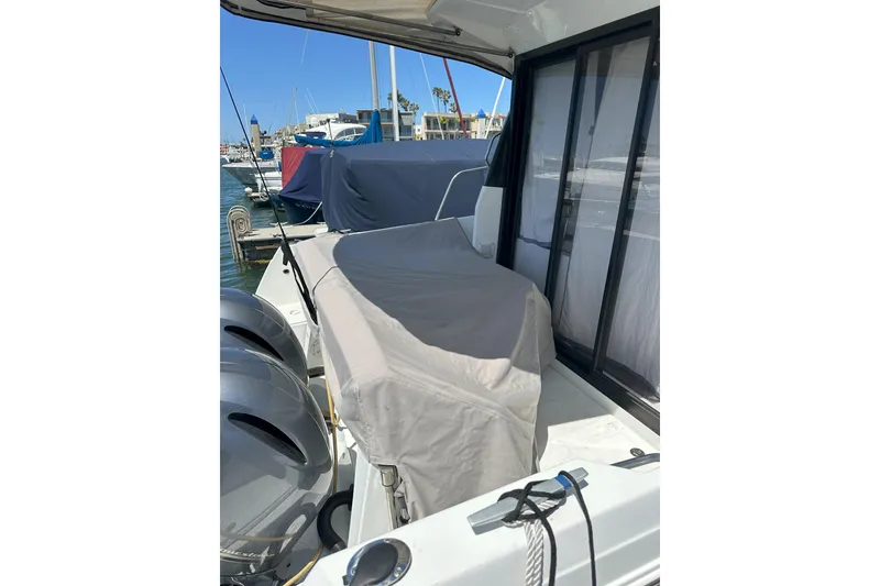 Slide: The Image of 2021 Jeanneau NC895 boat docked, covered seating area, and visible outboard motors. - 43