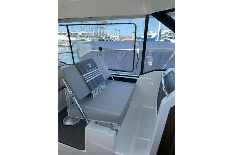 Slide: The Image of Interior of 2021 Jeanneau NC895 boat with cushioned seating and marina view. - 9