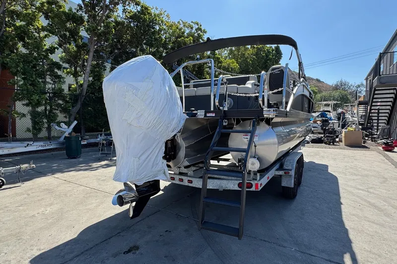 Slide: The Image of 2026 Barletta Cabrio 22UC pontoon boat on trailer, covered engine, outdoor setting. - 21