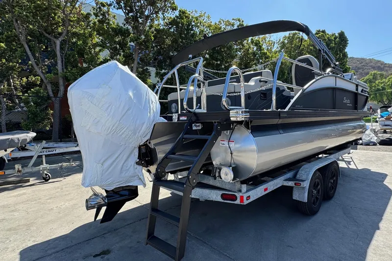 Slide: The Image of 2026 Barletta Cabrio 22UC pontoon boat on trailer, covered engine, outdoor setting. - 22