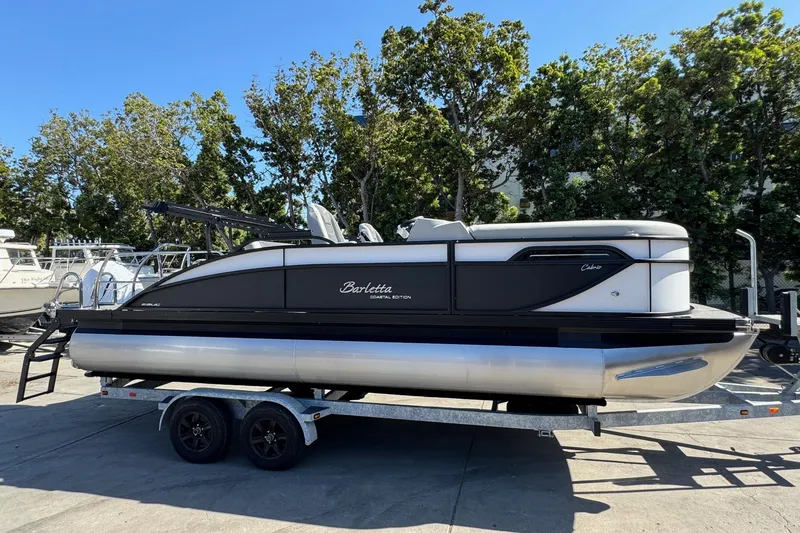Slide: The Image of 2026 Barletta Cabrio 22UC pontoon boat on trailer, parked outdoors. - 26