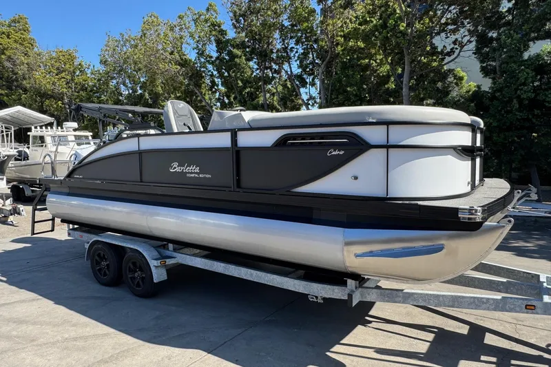 Slide: The Image of 2026 Barletta Cabrio 22UC pontoon boat on trailer, parked outdoors. - 27