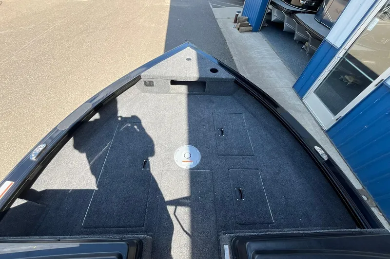 Slide: The Image of 2026 Crestliner 1850 Fish Hawk boat interior with carpeted deck and storage compartments. - 12