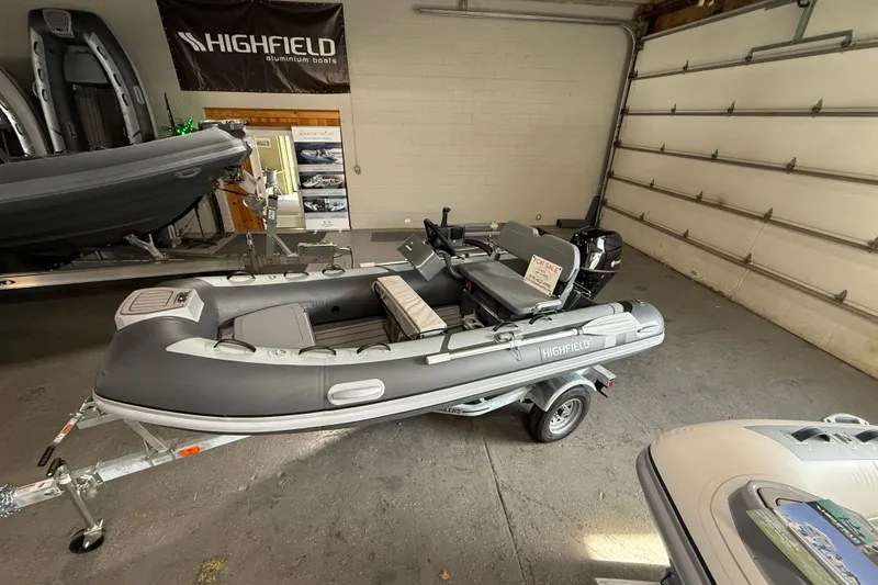 The Image of 2026 Highfield Classic 360 FCT inflatable boat in showroom, displayed on a trailer. - 1