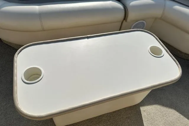 Slide: The Image of 2001 Crest Grand Caribbean boat table with cup holders, beige seating in background. - 18