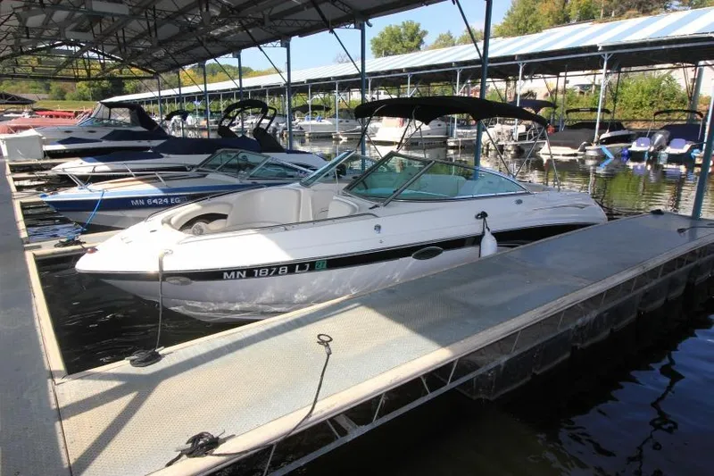 The Image of 2002 Chaparral 220 SSi boat docked in a marina with other vessels. - 0