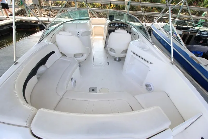 Slide: The Image of 2002 Chaparral 220 SSi boat interior with white seating and dashboard, docked at marina. - 5