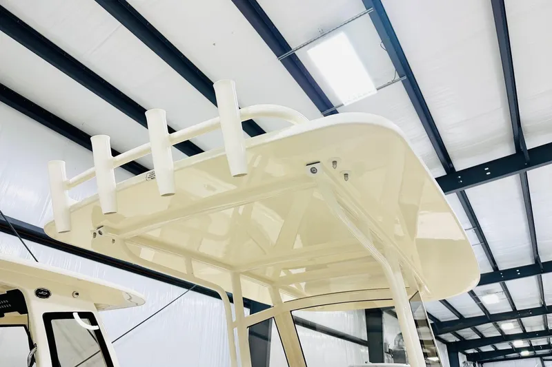 Slide: The Image of 2026 Scout 240 XSF boat's T-top with rod holders in a warehouse setting. - 7