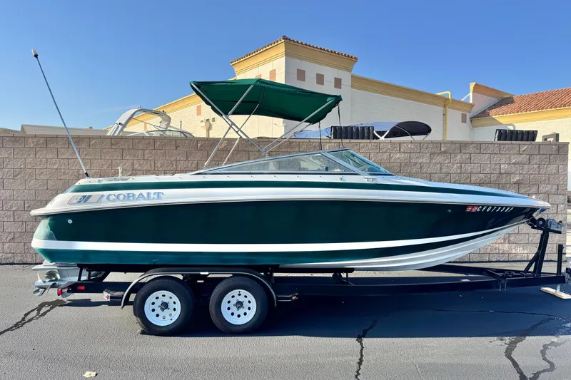 The Image of 1996 Cobalt 232 boat on trailer, green and white, parked outdoors. - 0