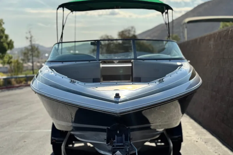Slide: The Image of 1996 Cobalt 232 boat with green canopy, parked on a sunny day. - 2