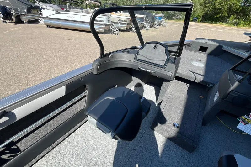 Slide: The Image of 2026 Crestliner 1750 Super Hawk interior with seating and windshield, parked near other boats. - 7