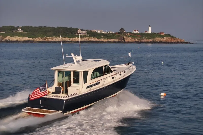 The Image of Back Cove 412 yacht cruising near a scenic coastline with lighthouse, 2026 model. - 0