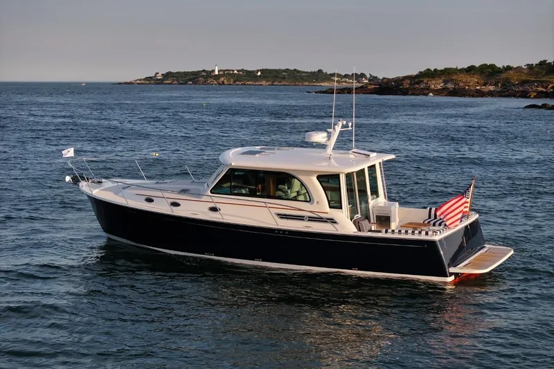 Slide: The Image of 2026 Back Cove 412 yacht cruising on calm waters near a rocky coastline. - 3