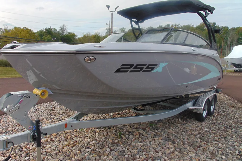 Slide: The Image of 2026 Yamaha Boats 255XD on trailer, sleek design, gray exterior, parked on gravel. - 6