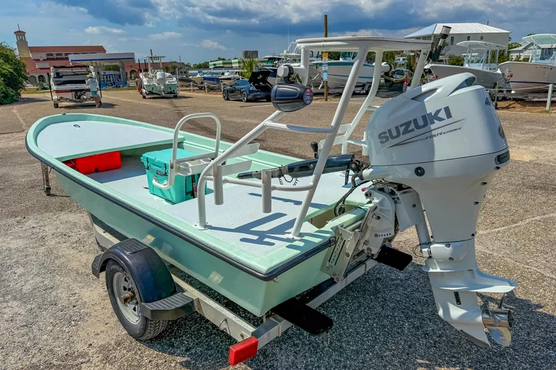 Slide: The Image of 15' Custom Tiller Skiff 2021 with Suzuki outboard motor on trailer, parked outdoors. - 3