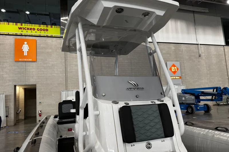 Slide: The Image of 2026 Highfield Sport 800 boat displayed indoors at an exhibition with restroom signage. - 13