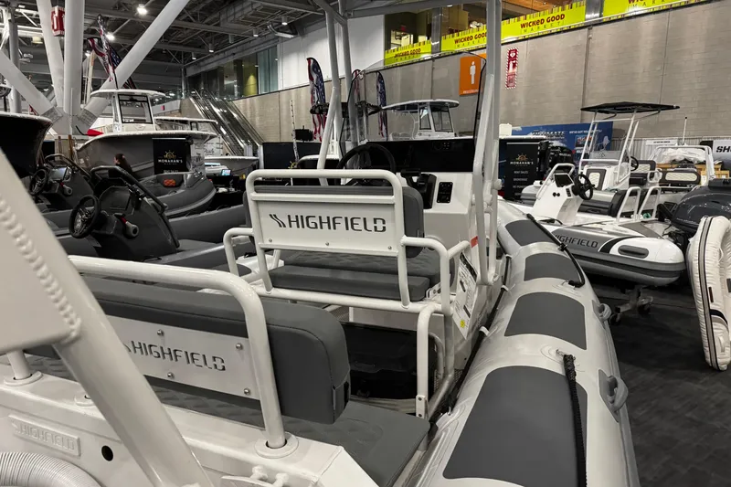 Slide: The Image of 2026 Highfield Patrol 540 boat displayed at an indoor exhibition, showcasing seating and controls. - 13