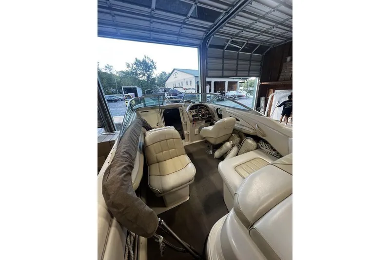 Slide: The Image of 1994 Sea Ray 220 boat interior in a garage, featuring beige seating and dashboard. - 5