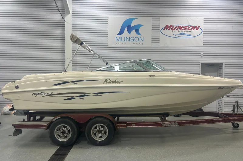 The Image of 2000 Rinker 212 Captiva Bowrider boat on trailer in showroom setting. - 1