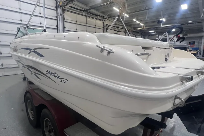 Slide: The Image of 2000 Rinker 212 Captiva Bowrider boat in a garage on a trailer. - 5