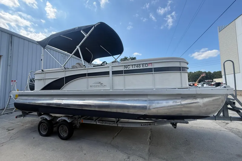 Slide: The Image of 2016 Bennington 22 SSRX pontoon boat on trailer, parked outdoors under blue sky. - 0