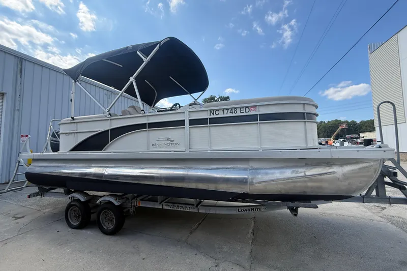 Slide: The Image of 2016 Bennington 22 SSRX pontoon boat on trailer, parked outdoors under blue sky. - 5