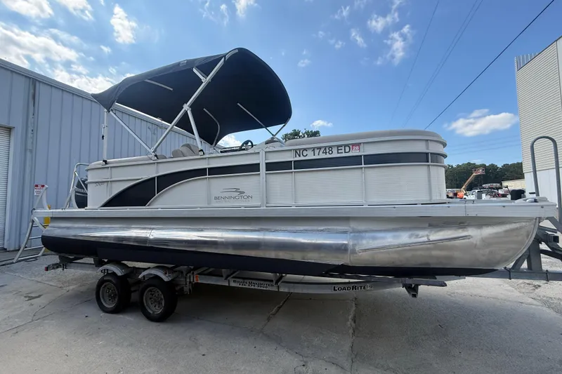 Slide: The Image of 2016 Bennington 22 SSRX pontoon boat on trailer, parked outdoors under blue sky. - 7