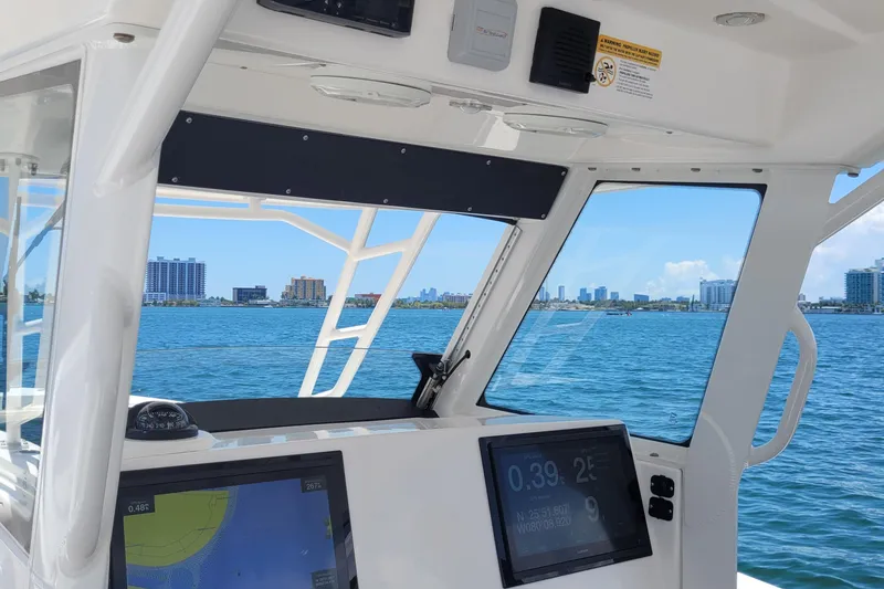 Slide: The Image of Interior view of 2018 Everglades 355 Center Console boat with navigation screens, overlooking city skyline. - 10