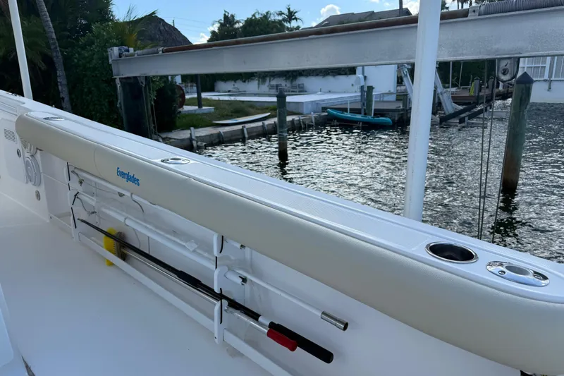 Slide: The Image of 2018 Everglades 355 Center Console boat docked by waterfront with fishing rod holders. - 23