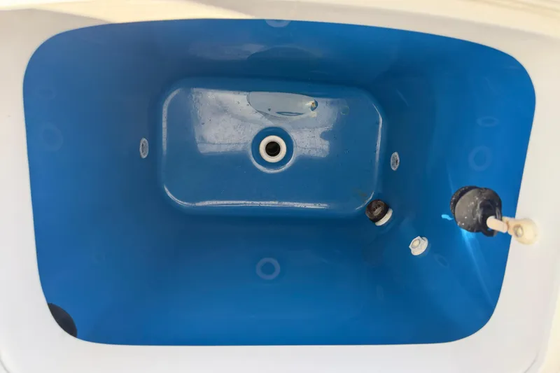 Slide: The Image of Livewell interior of 2018 Everglades 355 Center Console boat, featuring blue lining and drain. - 33