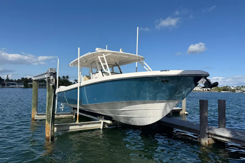 Slide: The Image of 2018 Everglades 355 Center Console boat on lift, blue sky background. - 7