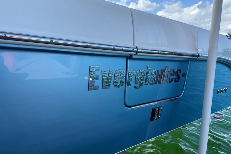 Slide: The Image of 2018 Everglades 355 Center Console boat with blue hull and chrome lettering. - 8