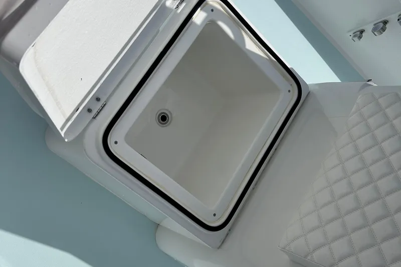 Slide: The Image of Open storage compartment on 2025 Dragonfly Boatworks Spanish Wells 21, featuring quilted seating. - 21