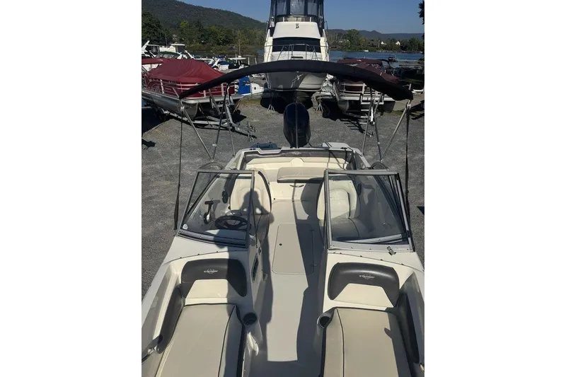 Slide: The Image of 2016 Stingray 191DC (OB) boat with open deck and canopy, docked near other boats. - 11