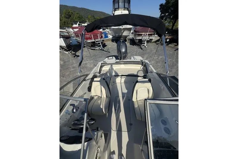 Slide: The Image of 2016 Stingray 191DC (OB) boat interior with seating and canopy, parked outdoors. - 14