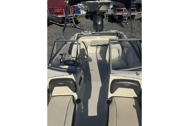 Slide: The Image of 2016 Stingray 191DC (OB) boat interior with seating and steering wheel, parked outdoors. - 17