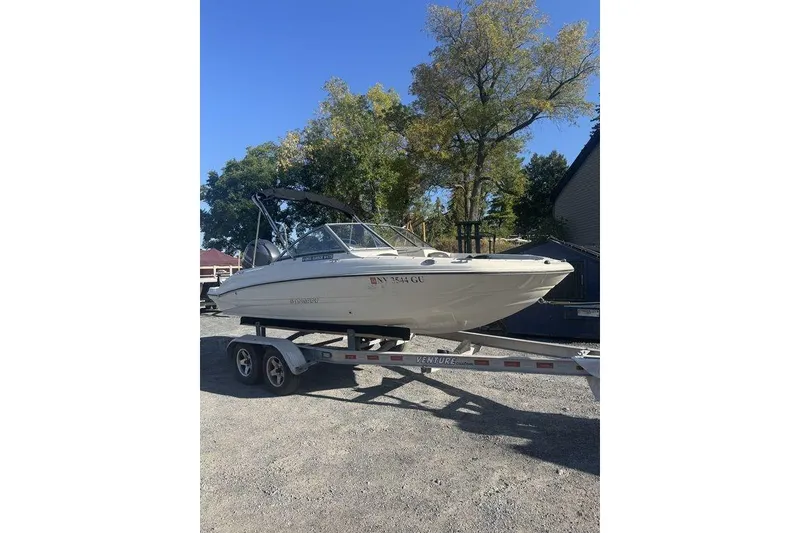Slide: The Image of 2016 Stingray 191DC (OB) boat on trailer, parked outdoors under clear sky. - 22